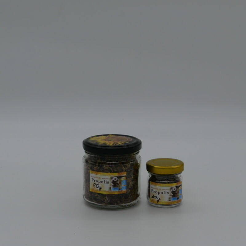 Kawałki naturalnego propolisu w przezroczystym słoiku na białym tle